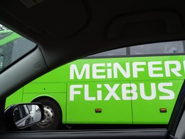 Ein Fernbus in grün mit der Aufschrift Mein Fern Flixbus,fotographiert aus einem danebenfahrendem Auto mit heruntergelassener Scheibe.