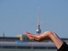 Der Berliner Fernsehturm Alexander in einer Hand vor blauem Himmel.