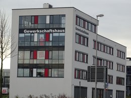 Ein hohes, großes  Gebäude in Grau- und Rottönen und der weißen Aufschrift Gewerkschaftshaus.