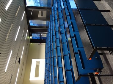 Ein leerer Hörsaal mit blauen hochgeklappten Sitzen.