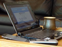 Ein Schreibtisch mit einem Computer, einem Telefon und einer Kaffeetasse.