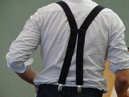 Rückenbild von einem Mann mit weiß-kariertem Hemd und Hosenträgern.