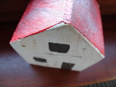 Ein weißes Holzhaus mit rotem Dach von schräg oben abgelichtet.