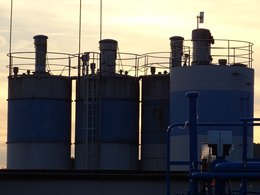 Vier Industriebehälter mit blauer Farbe vor einem Abendhimmel.