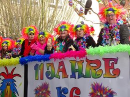 Ein Karnevalswagen mit als bunte Paradiesvögel verkleidete Menschen.