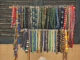 Ein Holzständer mit einer grossen Auswahl an bunten Perlenketten.