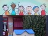 Mehrere gemalte, fröhliche Kinder unterschiedlicher Nationen auf einer Wand.