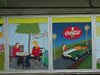 Zwei gemalte Bilder, das eine mit zwei Frauen bei der Kaffeepause und das andere mit einer Frau, einem Auto und einer Cola-Werbung.