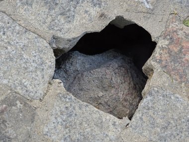 Ein großes Loch in einem Steinboden.