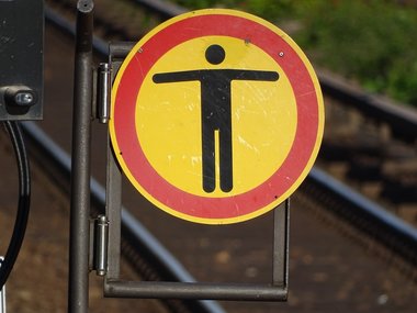 Ein rundes Schild in gelb mit einem roten Rand und einem schwarzen Mann in der Mitte mit ausgebreiteten Armen.