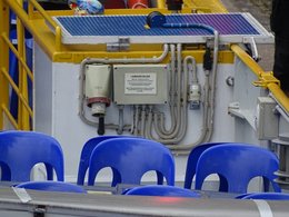 Ein Ausschnitt einer Maschine mit einem Landanschlußmöglichkeit und leeren blauen Plastikstühlen davor.