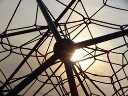 Das Netz eines Spielplatzklettergerüstes vor einem Sonnenuntergang.