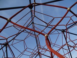 Das Netz eines Spielplatzklettergerüstes vor blauem Himmel.