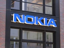 Ein blauer Leuchtschriftzug von Nokia an einer Hauswand mit Fenster.