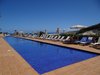 Ein länglicher Pool eines Hotels mit Liegen und Blick auf das Meer.