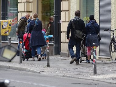 Eine Gruppe Passanten gehen auf einem Bürgersteig spazieren.