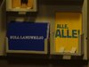 Ein Postkartenständer mit einer blauen Karte und der weißen Schrift: Null Langeweilig und einer gelben mit grüner Schrift: Alle,Alle!