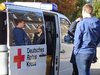 Ein weisser Bulli vom Roten Kreuz steht mit geöffneter Schiebtür auf einer Veranstaltung.