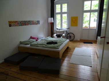 Ein Schlafzimmer mit einem Bett und Holzfußboden in einem Altbau.