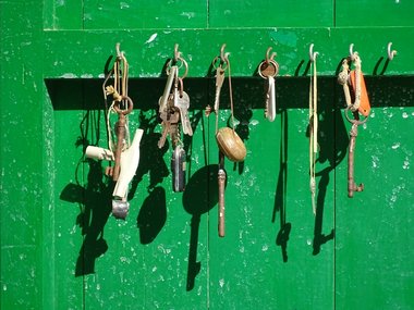 Eine grüne Holzwand mit einem Board an dem mehrere alte Schlüssel hängen.