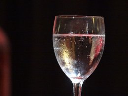 Ein Glas Sekt vor schwarzem Hintergrund.