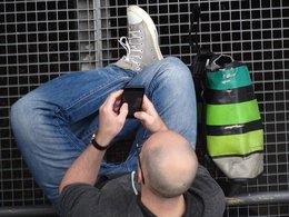 Ein Mann von oben aufgenommen hält ein Handy in den Händen.