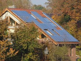 Ein Hausdach umgeben von Bäumen mit einer Solaranlage.
