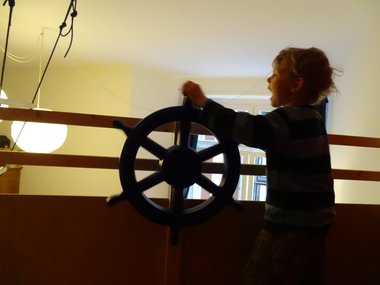 Ein Junge spielt mit einem Steuerrad eines Schiffes.