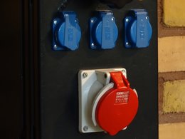 Ein Anschluß für Starkstrom mit einer roten Abdeckung sowie 3 blau abgedeckte Stromdosen.
