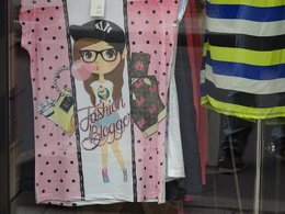 Ein Tshirt in rosa mit schwarzen Punkten und einem Mädchen mit Brille und Kaugummi und der Aufschrift Fashion Blogger.
