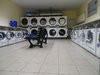 Der Einblick in einen Waschsalon mit zahlreichen Maschinen und einer Sitzbank in der Mitte.
