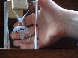Eine durchsichtige Weltkugel, die in Glas eingearbeitet ist mit einer Hand im Hintergrund.