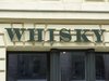 Ein Geschäftsfenster mit einem Buchstabenschild für Whisky in grün darüber.