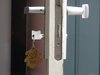 Großaufnahme eines Wohnungsschluessels der im Schloß steckt und an dem ein Schlüsselanhänger baumelt.