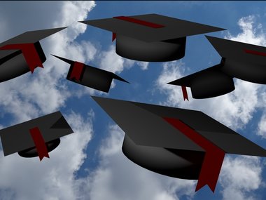 Man sieht mehrere Hüte fliegen, die beim Universitätsabschluss vergeben werden.