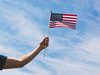 Eine Hand hält eine kleine, amerikanische Flagge.