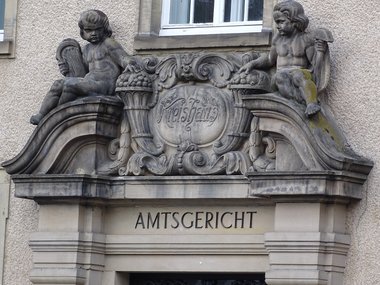 Der kunstvolle Eingang eines Amtsgerichtes mit in Stein gehauenen Engeln.