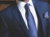 Der Oberkörper eines Managers mit blauem Anzug und gepunkteter Krawatte.