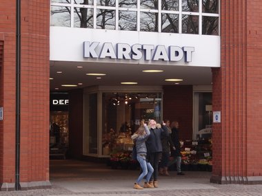Das Kaufhaus Karstadt mit zwei Mädchen unter dem Eingangsschild, die nach oben zeigen.