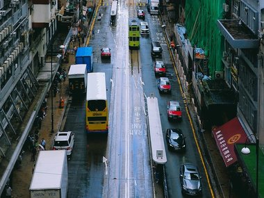 Eine Straße durch eine Großstadt in Asien mit verschiedenen Fahrzeugen.