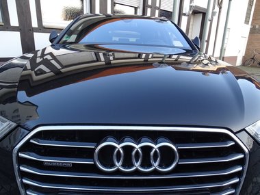 Ein glänzender, schwarzer Audi aus der Motorhaubenperspektive.