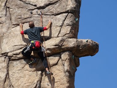Ein Mann klettert an einer Felswand steil nach oben.