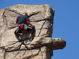 Ein Mann klettert an einer Felswand steil nach oben.