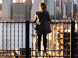 Ein USA-Expat steht auf einem Zaun und schaut auf die Skyline von New York.