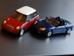 Ein blauer Porschecabrio und ein roter Mini als Spielzeugautos stehen nebeneinander.