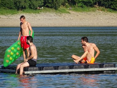 Eine Badeinsel auf einem See mit tobenden Jugendlichen.