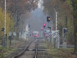 Bahnschienen mit weitem Blick und einer heranfahrenden Eisenbahn.