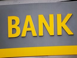 Das Wort Bank in gelb mit plastischen Buchstaben an einer Wand.