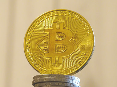 Bitcoin ATM: Das Bild zeigt einen Bitcoin auf einem Stapel Münzen.