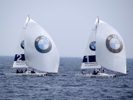 Segelboote mit dem BMW-Symbol auf offener See mit Wind in den Segeln.